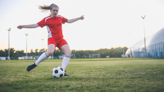 young woman playing soccer on field