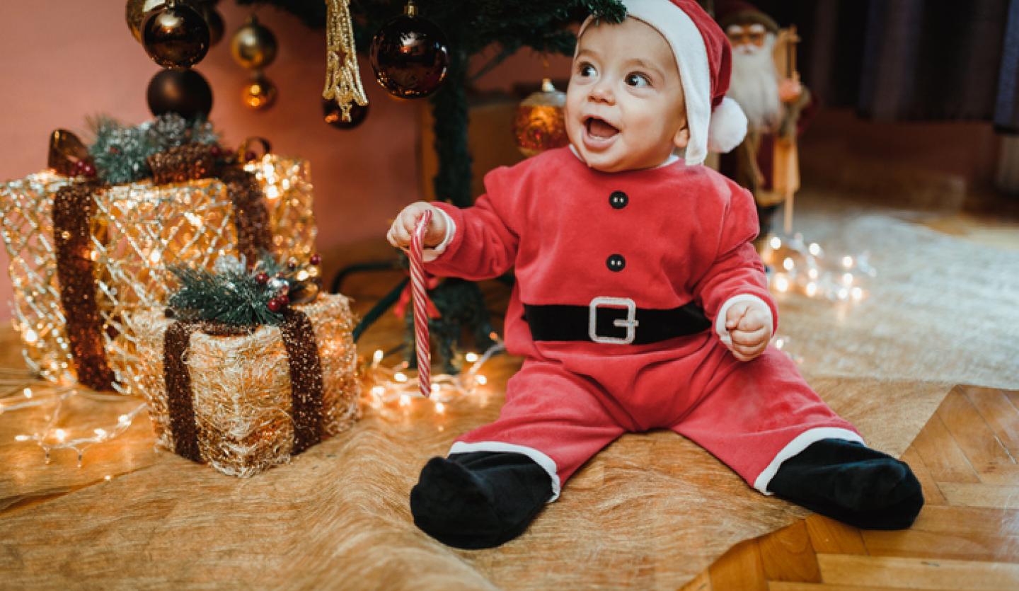 baby in santa suit under christmas tree