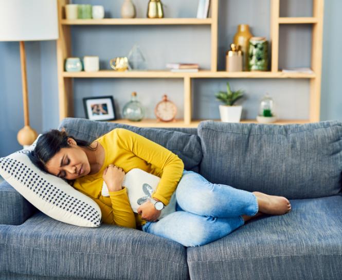 woman with heating pad on couch