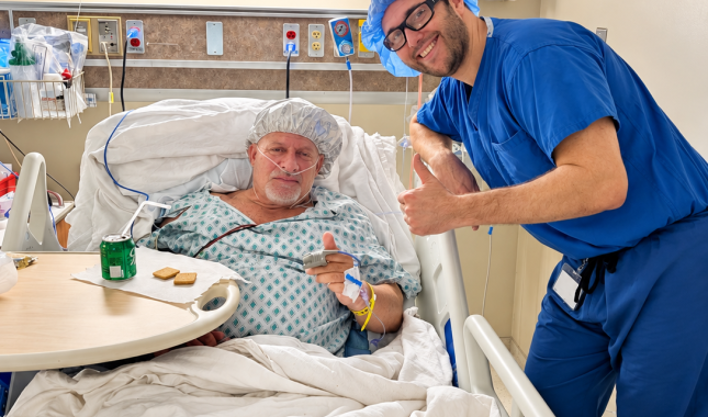 Doctor poses next to a patient in his hospital bed 