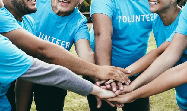 Group of people in blue volunteer shirts with hands together