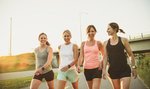 Four women walking alongside each other in a park