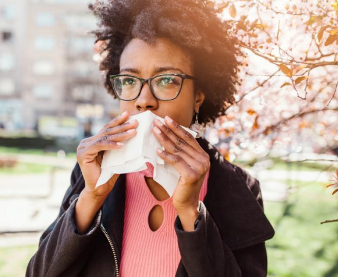 woman outside holding tissue to mouth